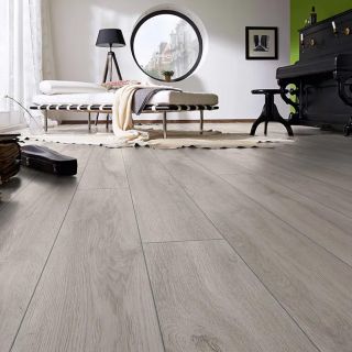 Una habitación con suelo laminado color roble con un piano y una cama