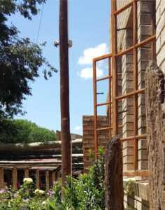 Poste De Luz De Madera Instalado Junto A Una Vivienda, Utilizado Para Soporte Eléctrico En Exteriores Rurales