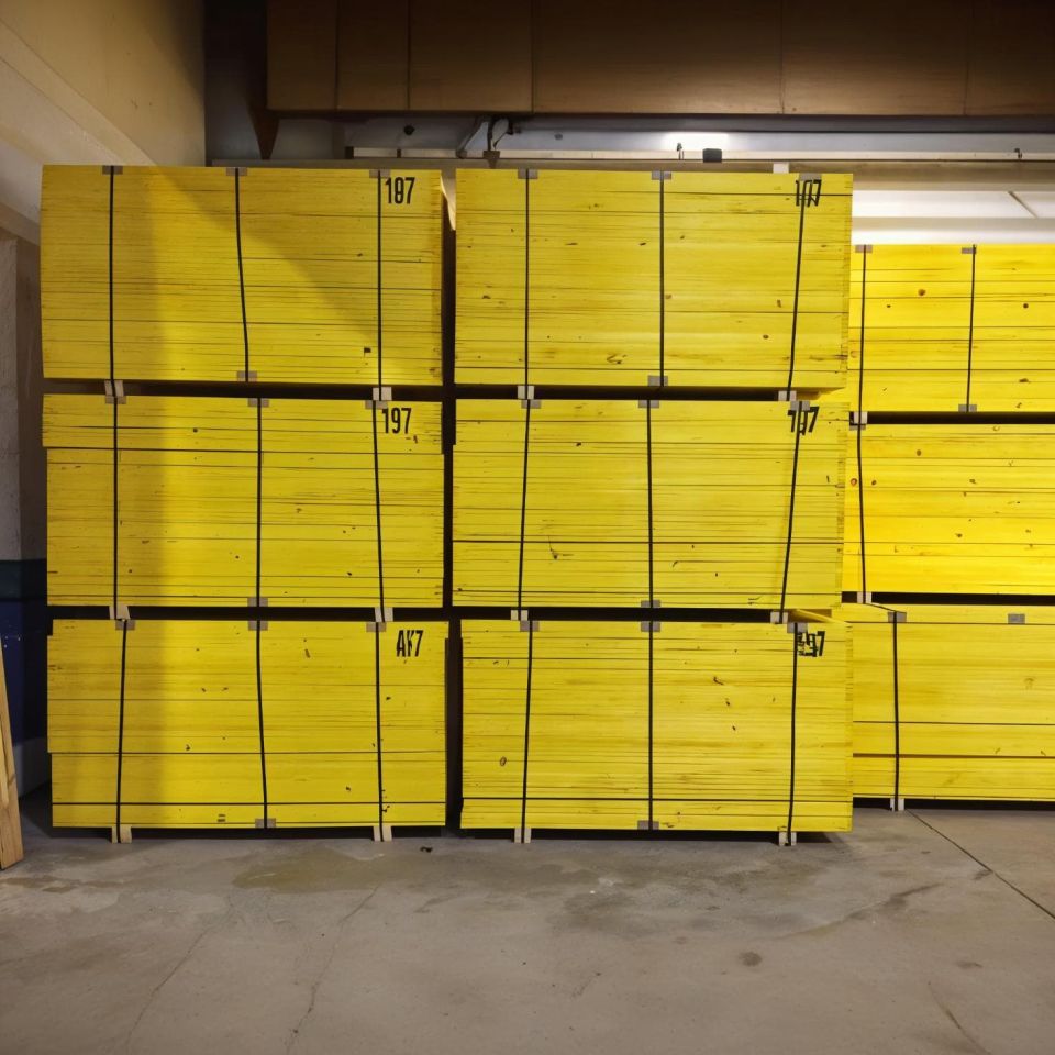 Pilotes de tableros de encofrar de color amarillo almacenados en interior de almacén, preparados para uso en obra y construcción