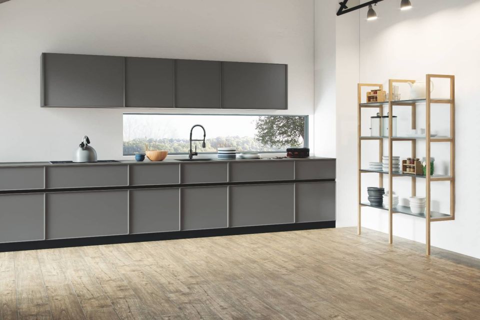 Cocina a medida minimalista con gabinetes gris RAL 7030, gola negra y estantería de madera.