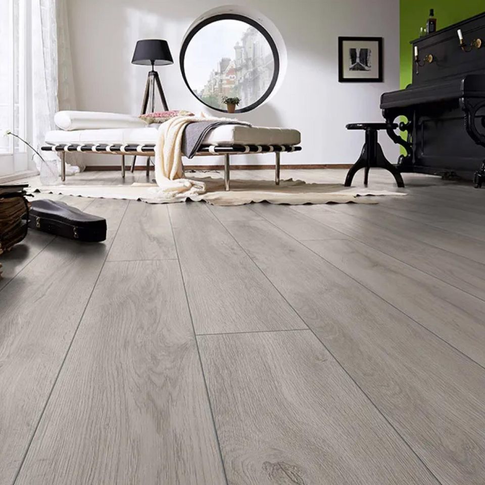 Una habitación con suelo laminado color roble con un piano y una cama