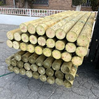 Palet de postes de madera redondos tratados, ideal para cercados, vallas y jardines.