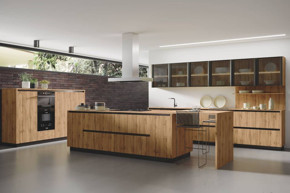 Cocina a medida con gabinetes de madera ligna, gola negra, isla central y vitrina con vidrio.