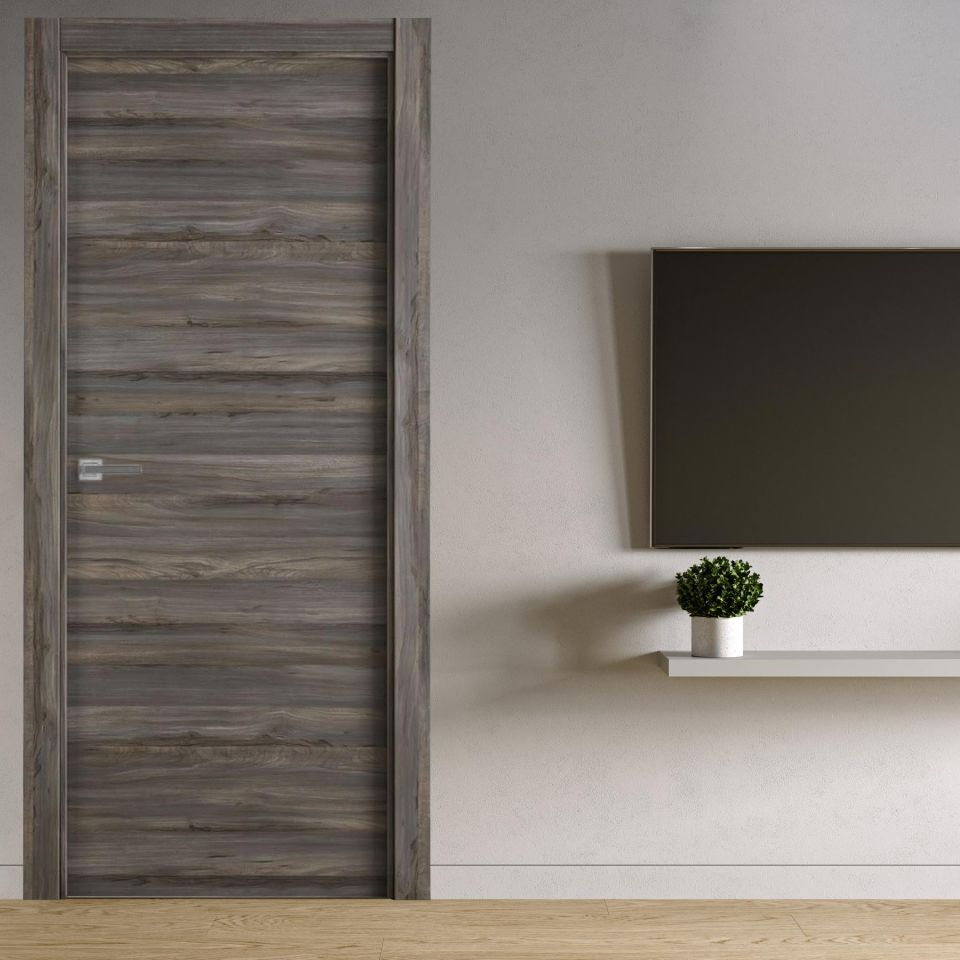 Puerta laminada X1000 Vulcano instalada en interior moderno, diseño en veta gris y tirador metálico.